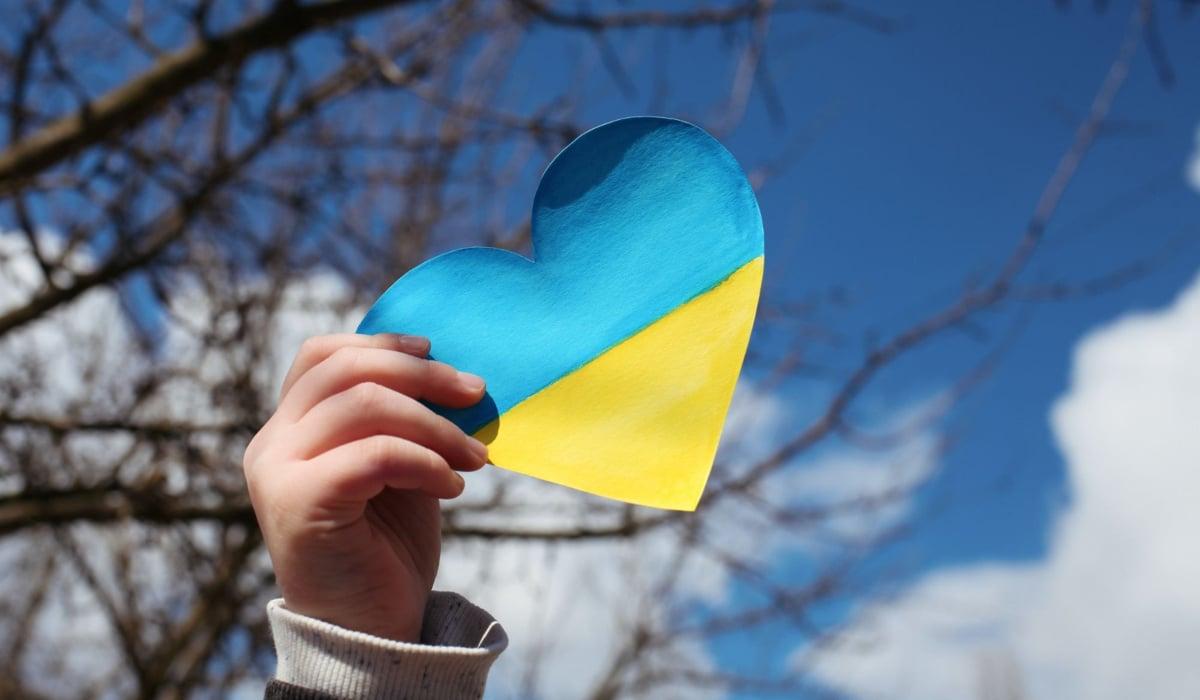 Person som håller i ett hjärtformad ukrainsk flagga