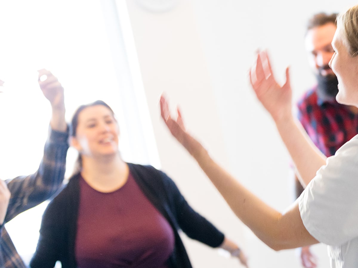 Suddig bild av fyra personer som står mot varandra och röd armarna.