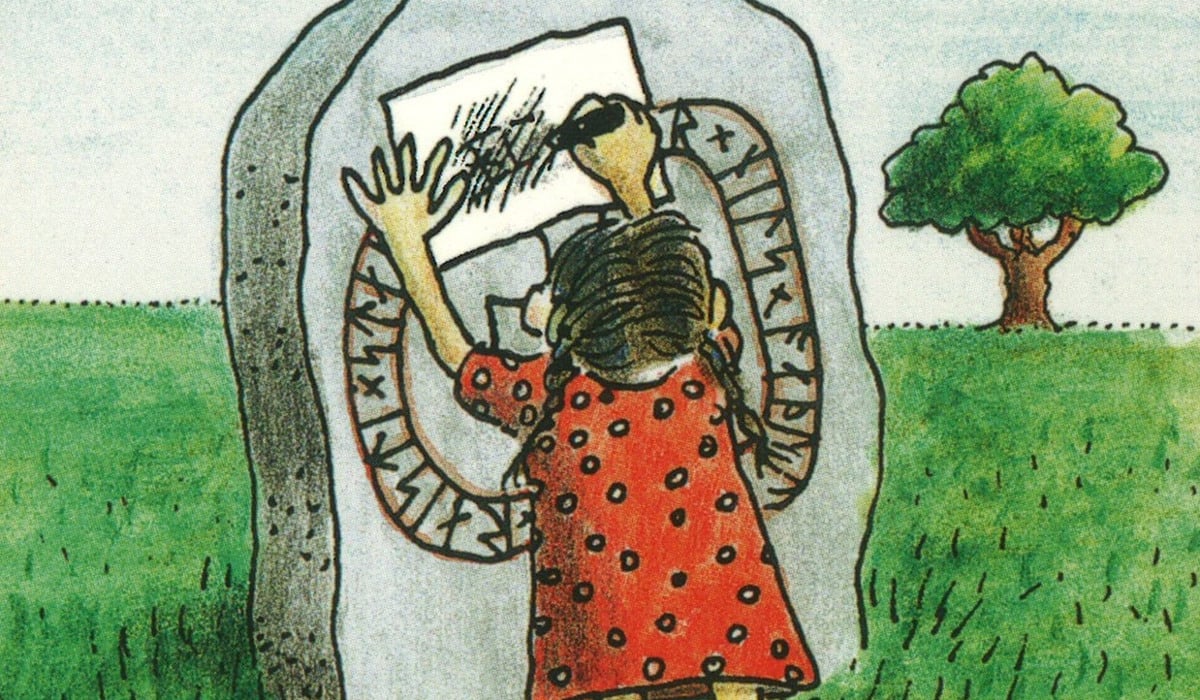 En figur står framför en runsten och kalkerar av inskriften.