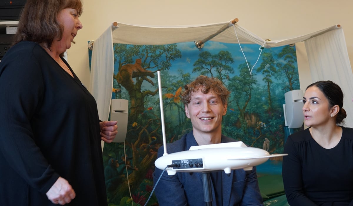 Tre personer framför ett musikintrument som ser ut som ett disk som flyger i luften. Disken skapar ljud vid rörelse.