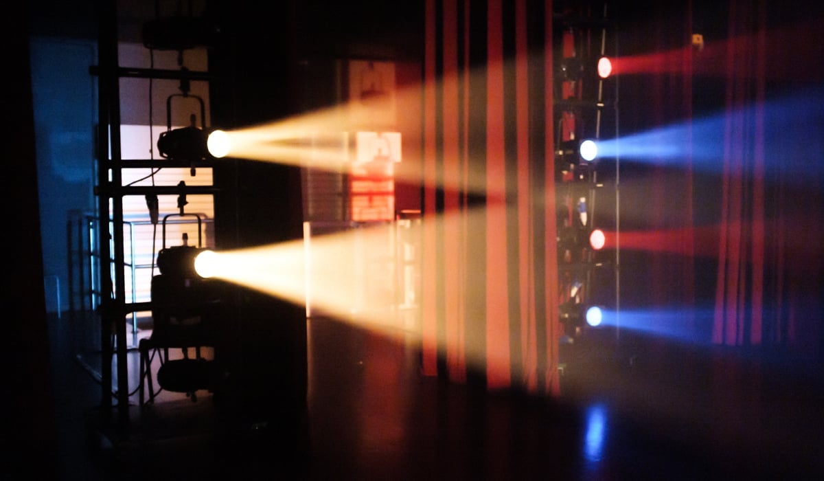 Scenljus som riktas ut förbi en röd ridå.