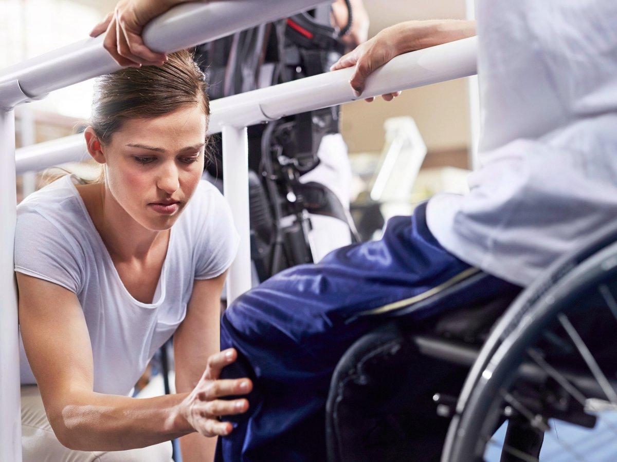 Person i rullstol får hjälp med gåträning