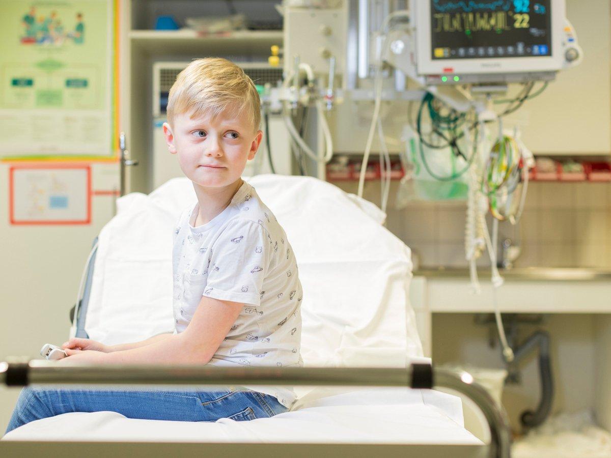 Barn sitter i sjukhussäng på akutrum