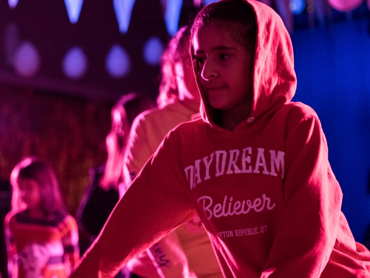 Barn och unga som dansar under partyflaggor och ballonger med festlig belysning.