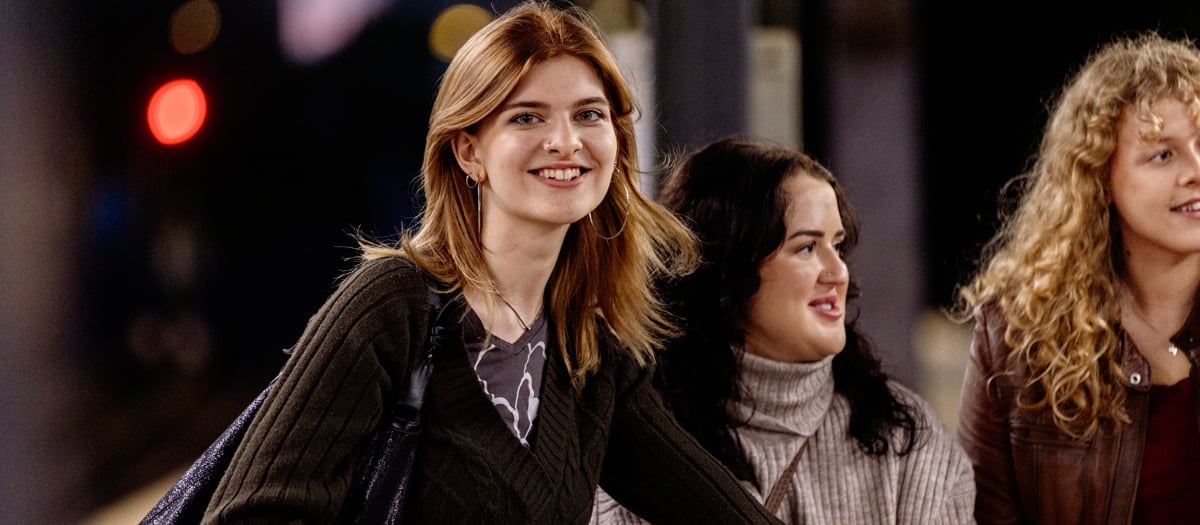 Tre unga tjejer, varav en tittar in i kameran