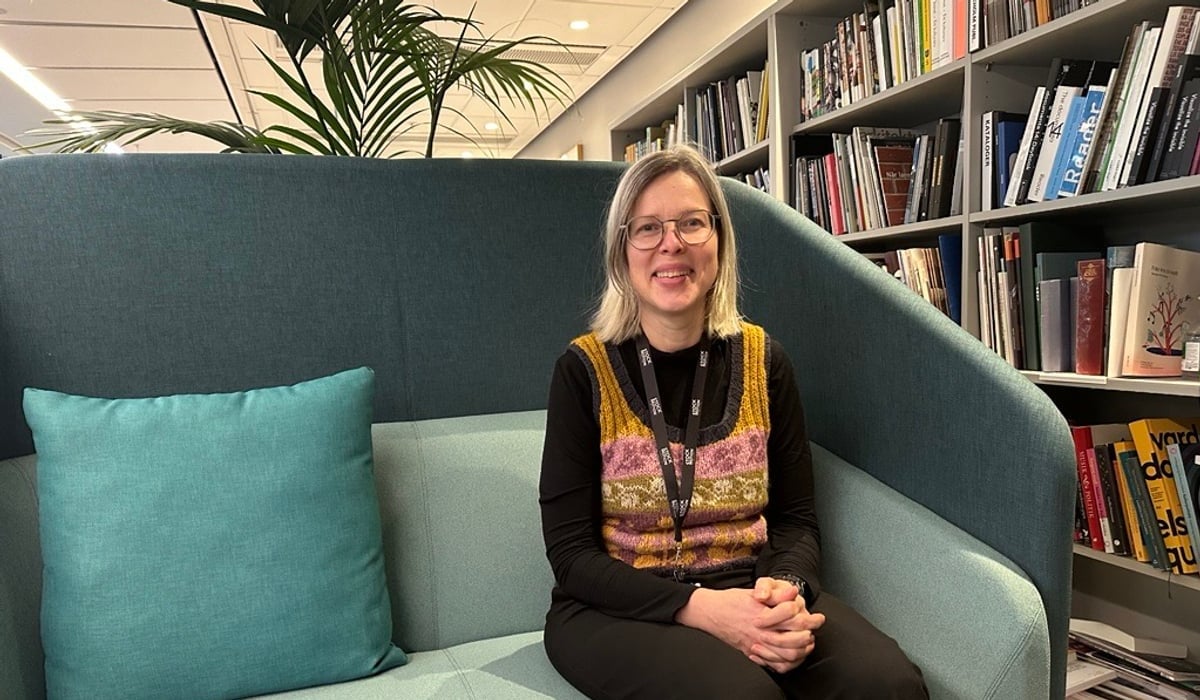 En kvinna sitter i en soffa i ett bibliotek.