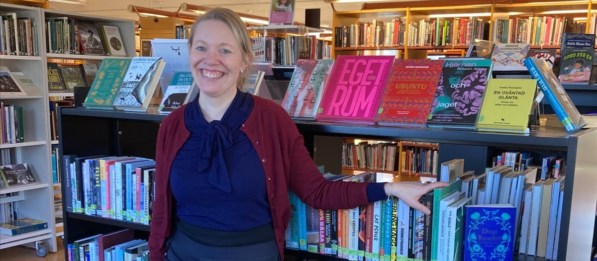 En kvinna som står framför en bokhylla fylld med böcker.