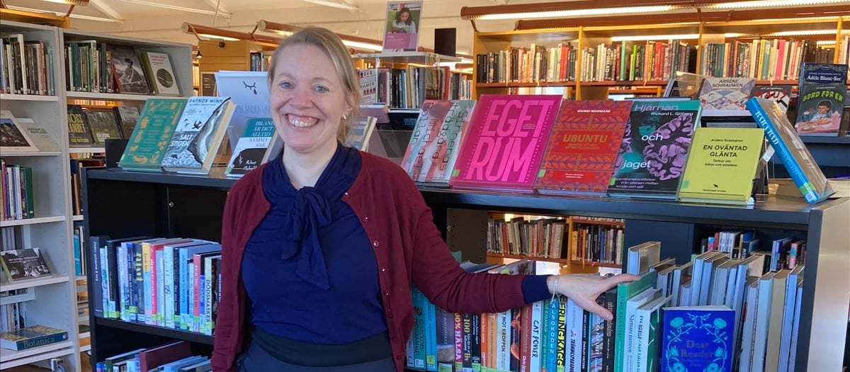 En kvinna som står framför en bokhylla fylld med böcker.