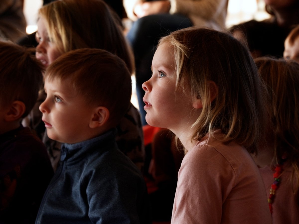 Barn som sitter och tittar koncentrerat åt samma håll (föreställningen de tittar på är utanför bilden)