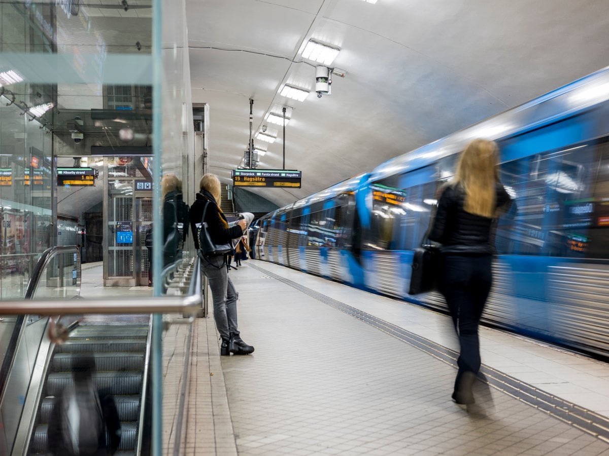 Personer väntar på tunnelbanan som rullar in i hög fart
