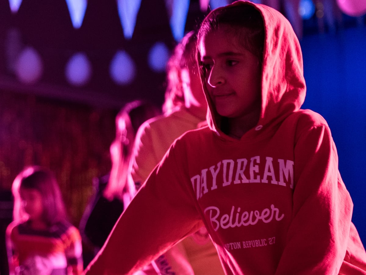 Barn och unga som dansar under partyflaggor och ballonger med festlig belysning.