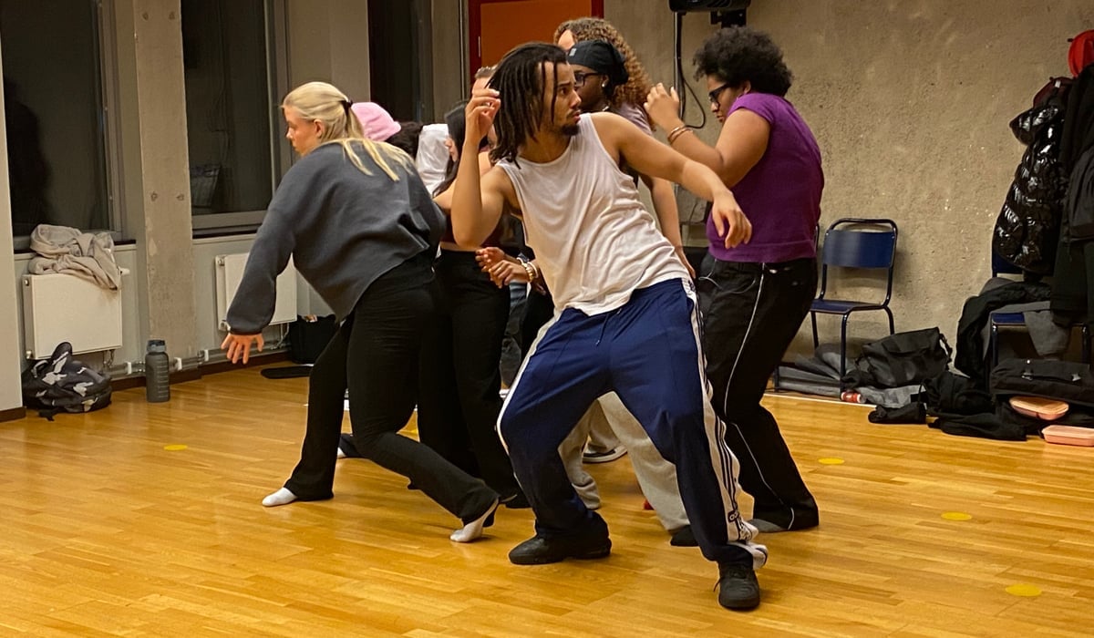 En grupp människor i träningskläder som står nära varandra och gör rörelser tillsammans