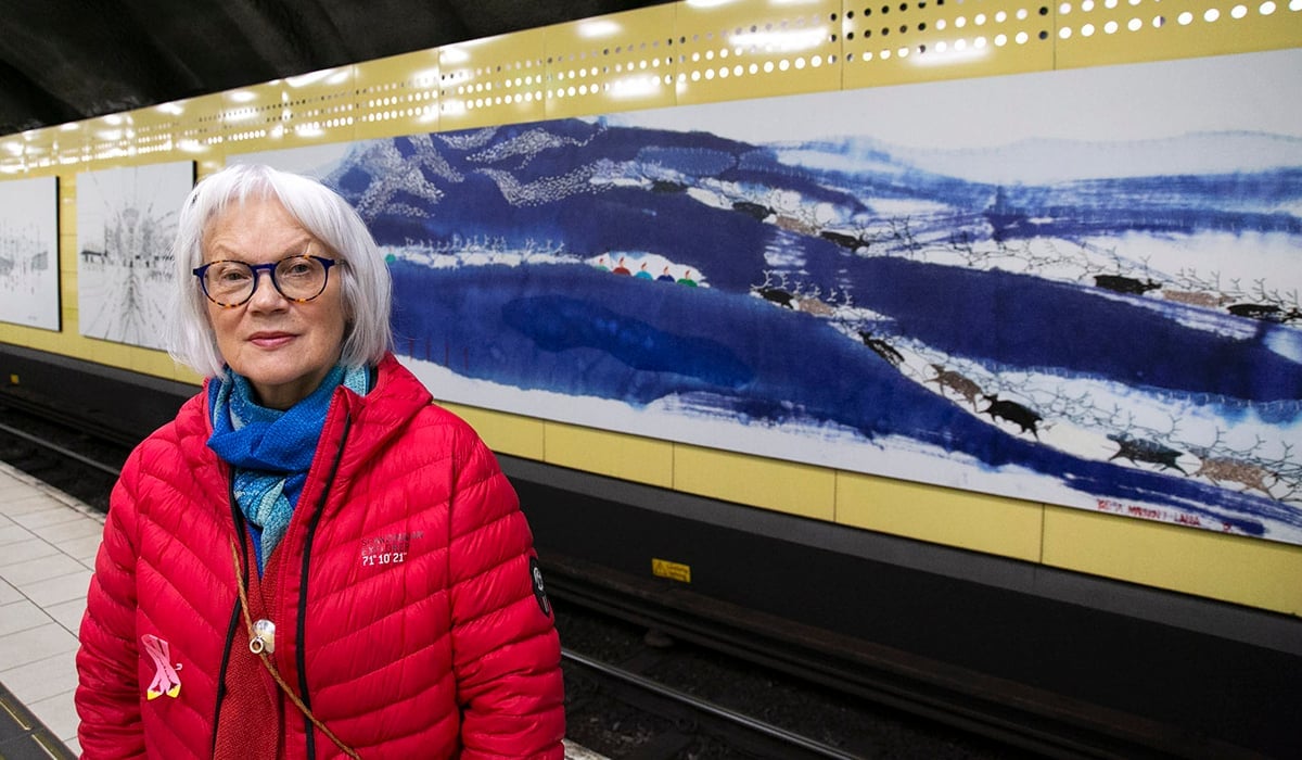Brita framför konsttavla på Fridhemsplan med motiv från Sapmi.