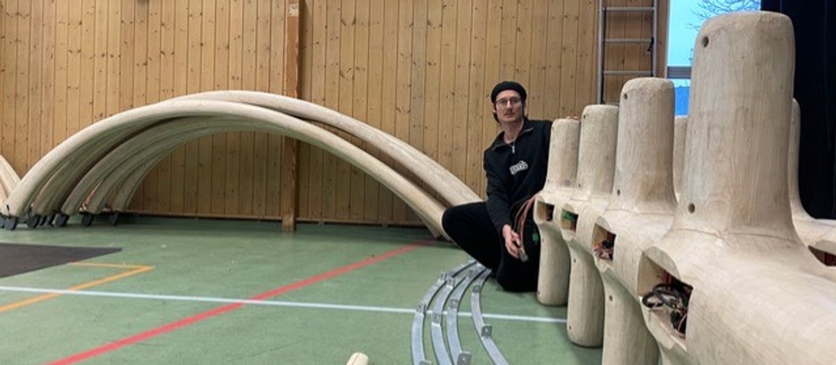 En man sitter på i en idrottshall bredvid en ljus träanläggning.