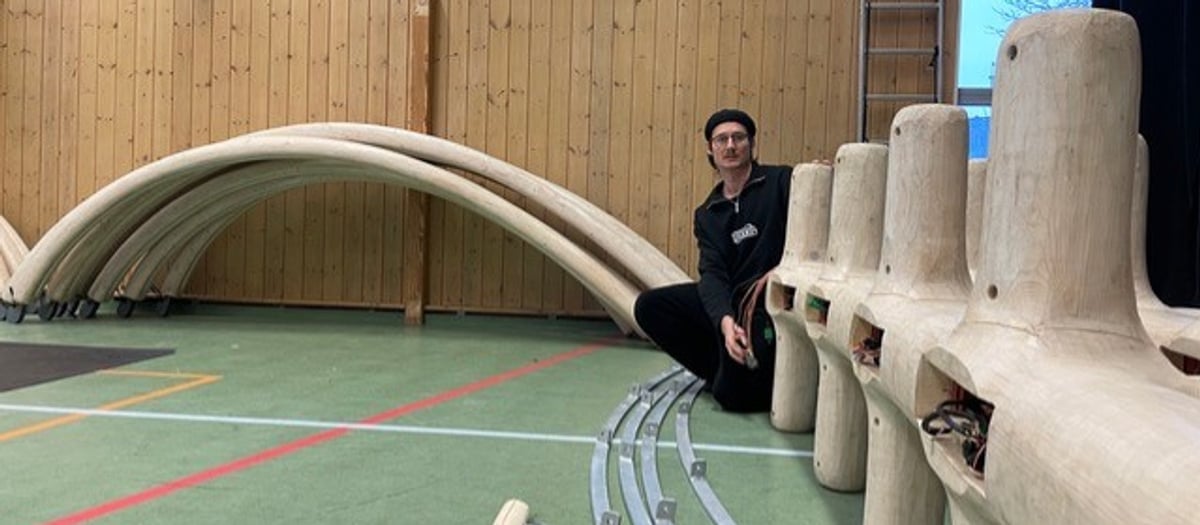 En man sitter på i en idrottshall bredvid en ljus träanläggning.