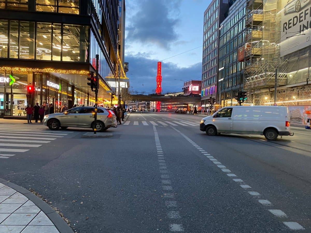 Två bilar svänger av från Hamngatan i kvällsljus