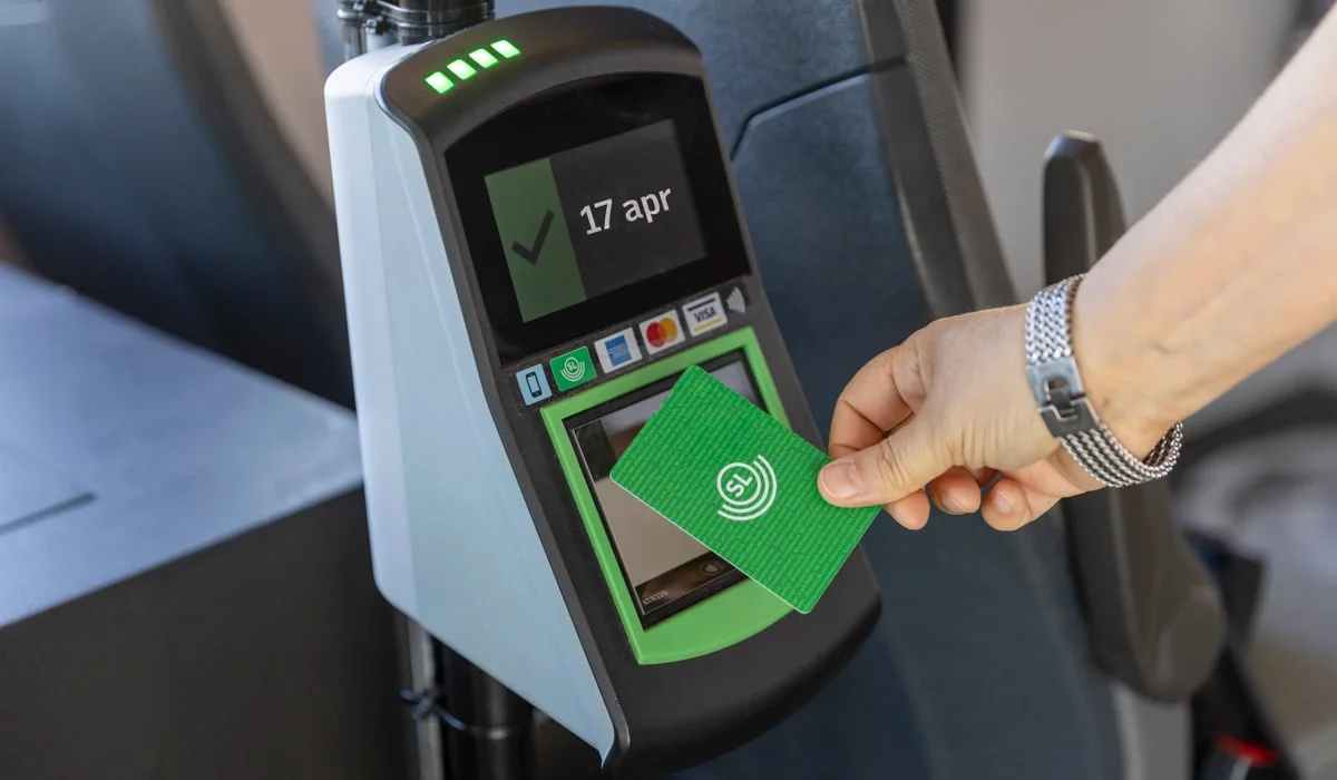 En person som blippar ett grönt kort mot en kortläsare.