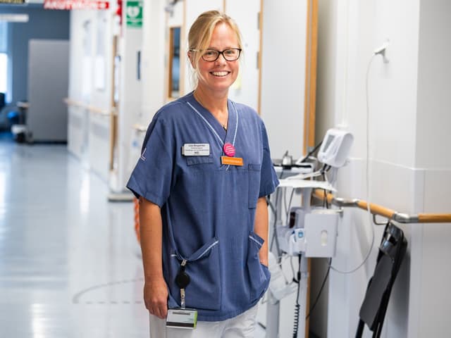 Kvinnlig arbetsterapeut i sjukhuskorridor.