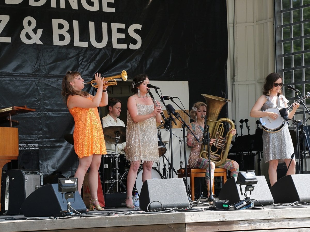 Ett band på scen med texten Huddinge jazz och blues på väggen bakom scenen.