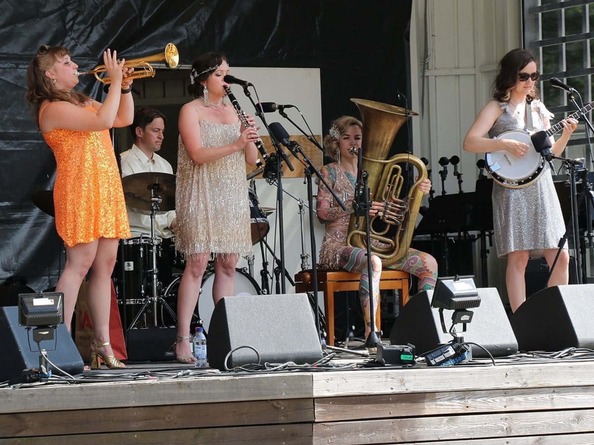 Ett band på scen med texten Huddinge jazz och blues på väggen bakom scenen.