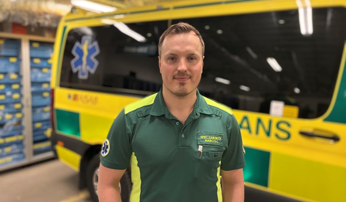 En man står framför en gul och grön ambulansbuss.