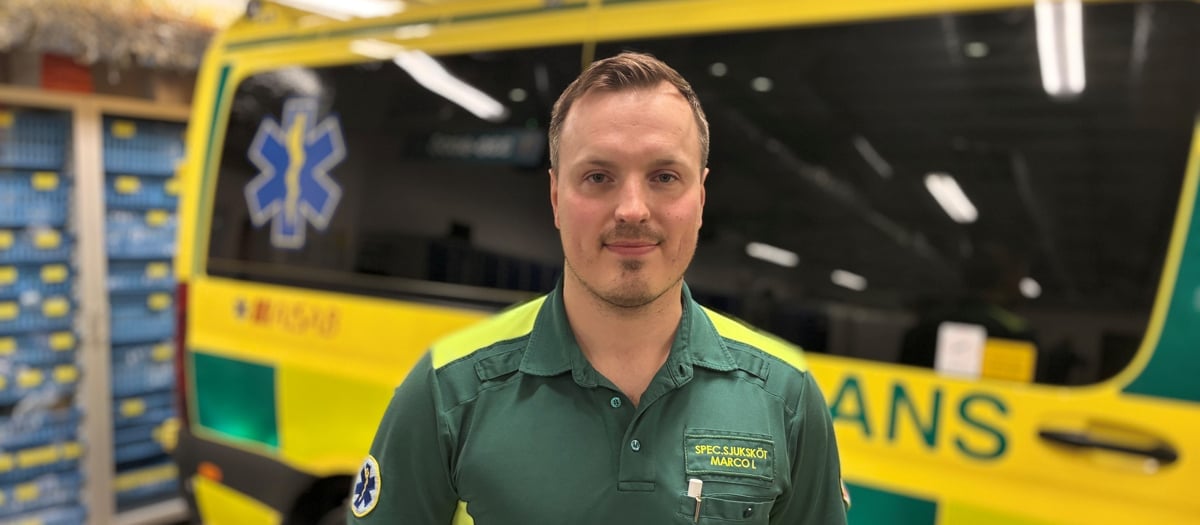 En man står framför en gul och grön ambulansbuss.