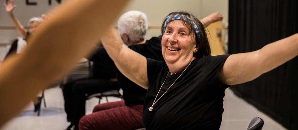 En kvinna som sitter i en stol med armarna i luften.