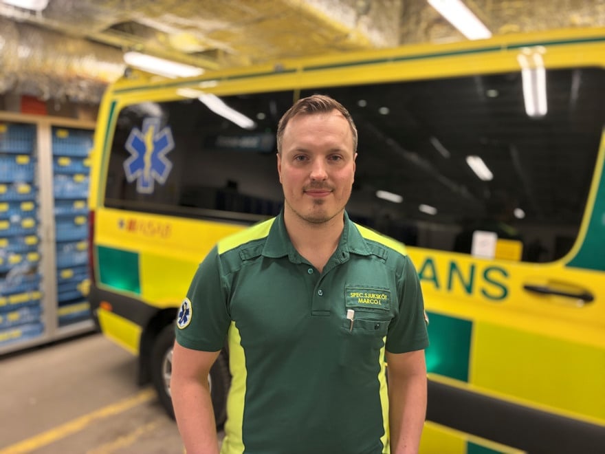 En man står framför en gul och grön ambulansbuss.