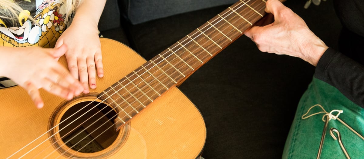 Händer som håller i en gitarr.