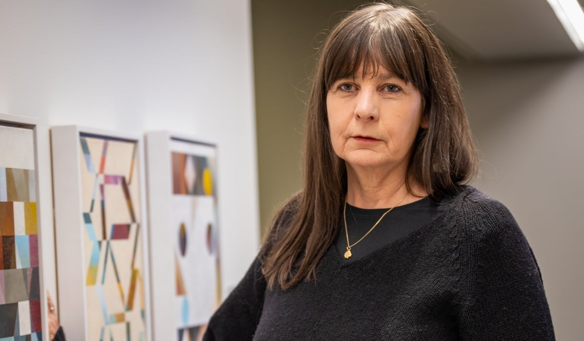 En kvinna som står bredvid en vägg med målningar på.