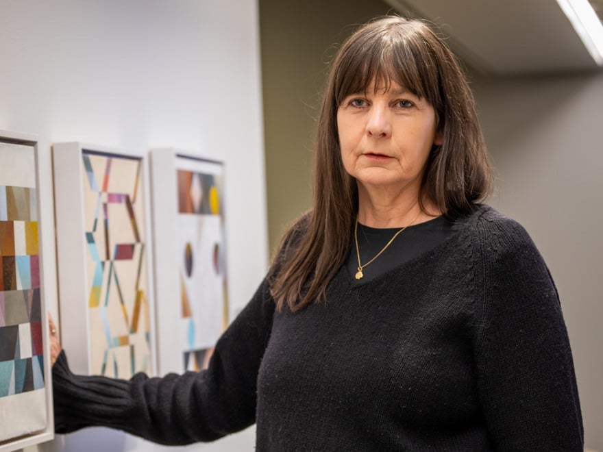 En kvinna som står bredvid en vägg med målningar på.