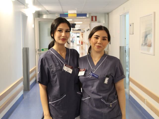 två kvinnor i vårdkläder tillsammans i sjukhuskorridor