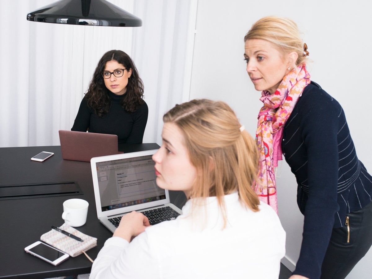 Foto på flera personer som sitter runt ett bort med bärbara datorer framför sig.