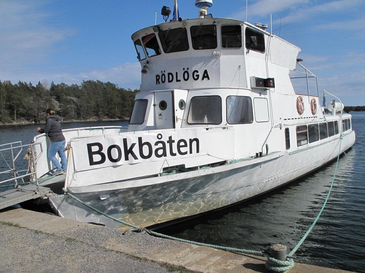 Vit båt med svart text Bokbåten ligger vid kaj.