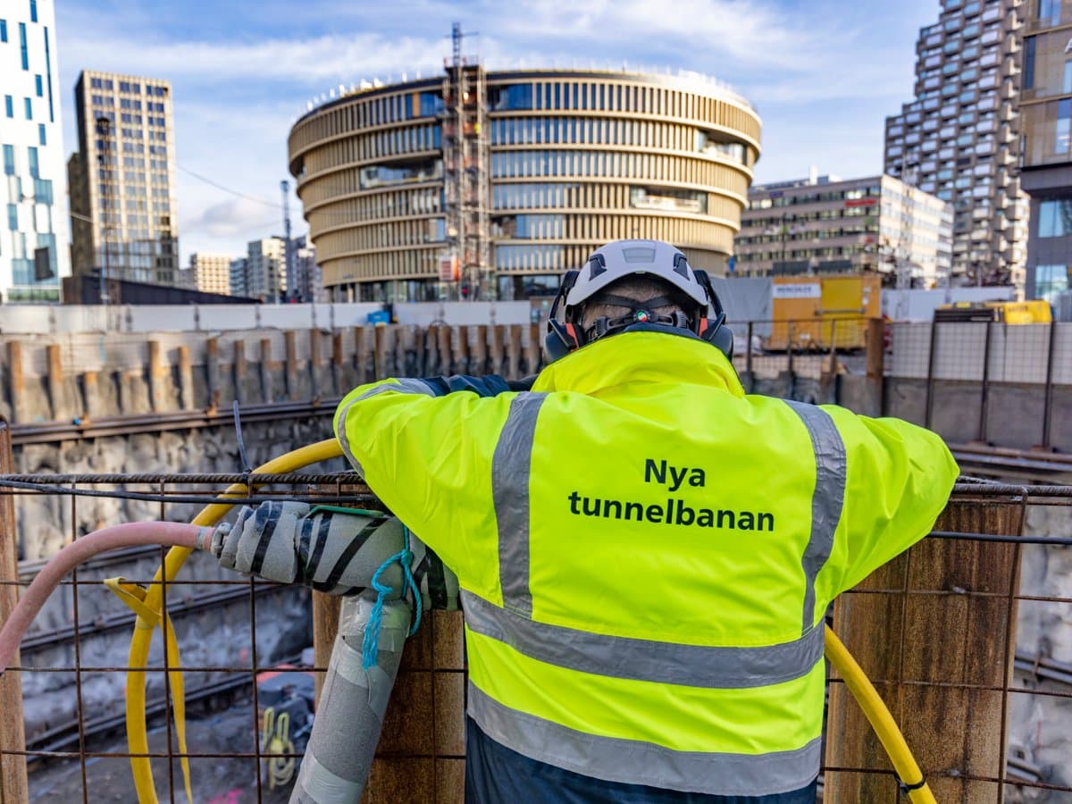 Foto av byggarbetare bakifrån med texten "Nya tunnelbanan" skriven på jackan