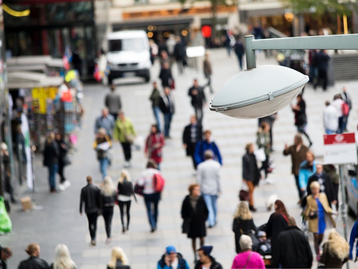 Människor som går på en gata. I förgrunden syns en gatlampa