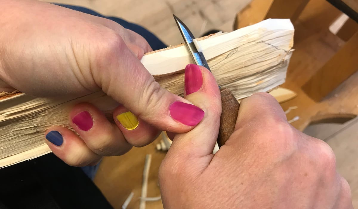 Händer som täljer med kniv, fingrarna har naglar målade i olika färger