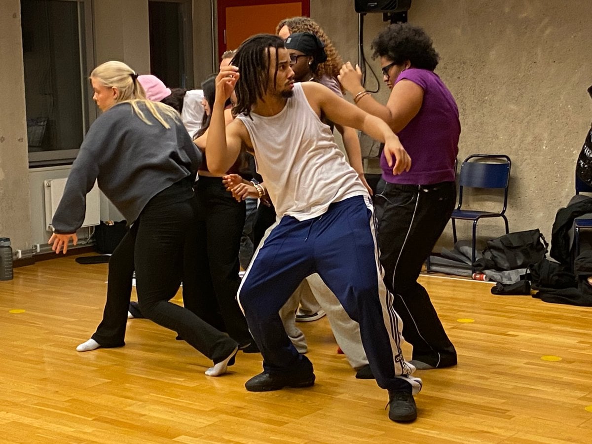 En grupp människor i träningskläder som står nära varandra och gör rörelser tillsammans