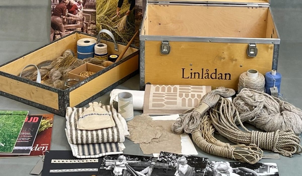 En trälåda med texten "Linlådan" och en massa saker gjorda av lin samt redskap för att slöjda i lin.