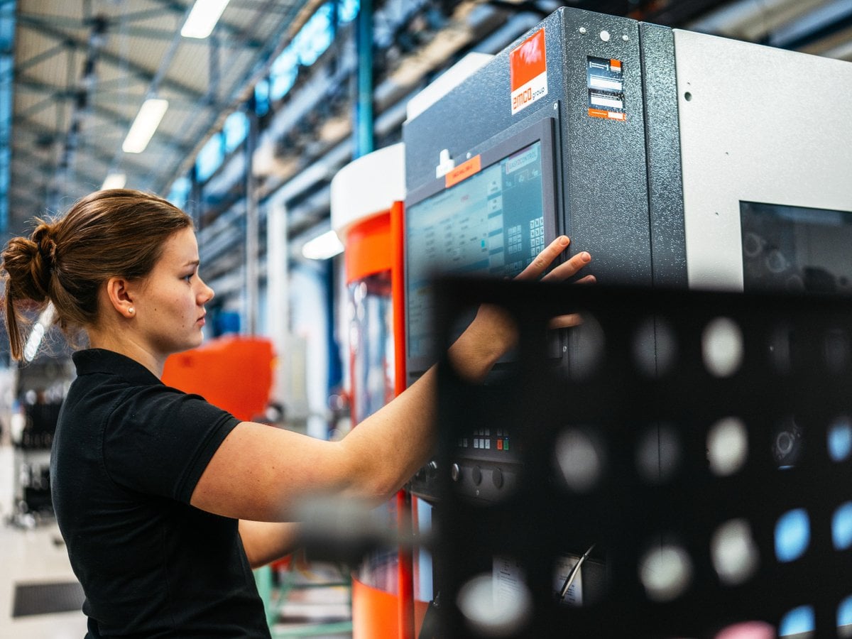 Foto på en kvinna trycker på en stor skärm framför sig.