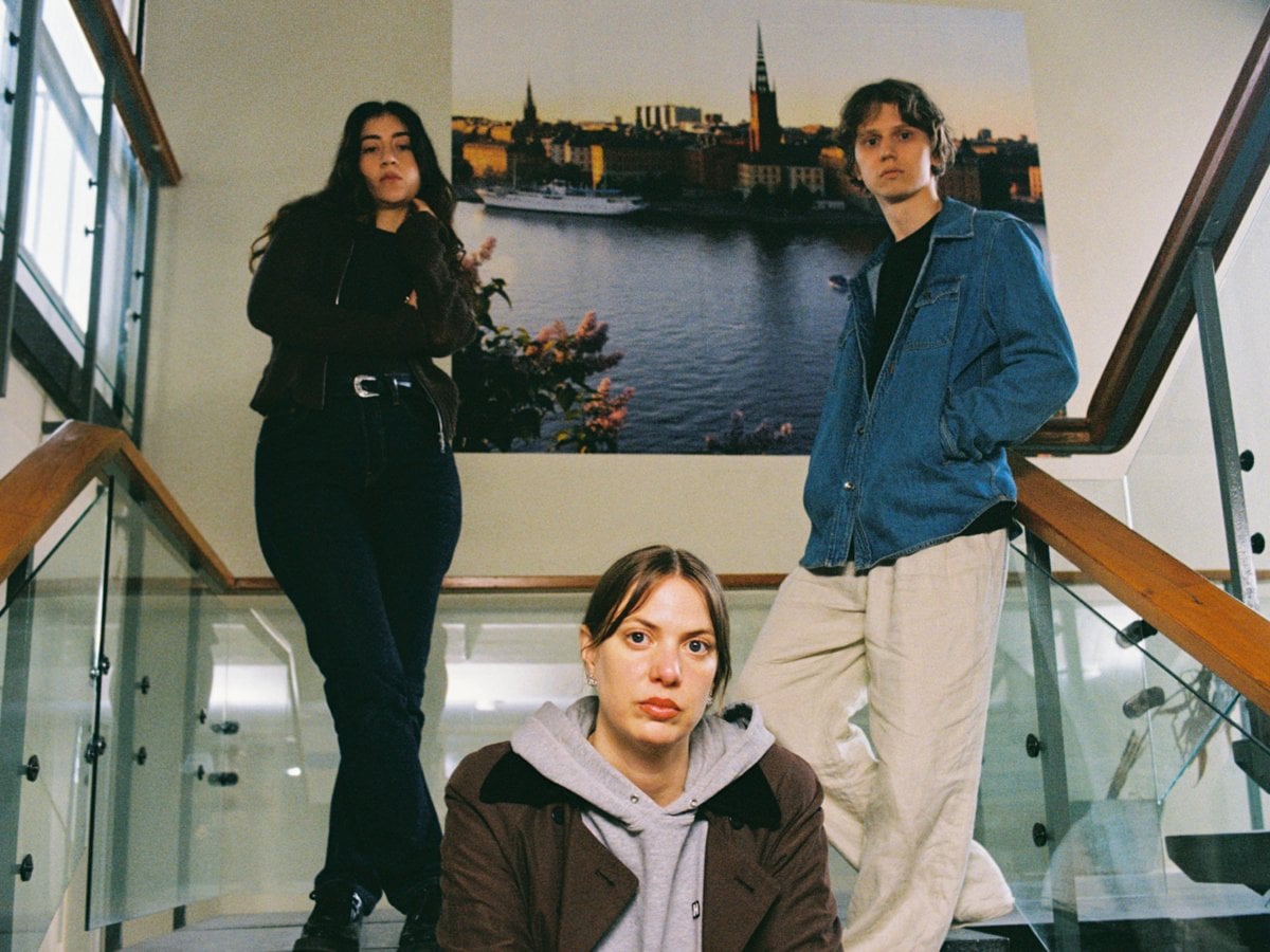 Tre personer i en trappa tittar in i kameran.