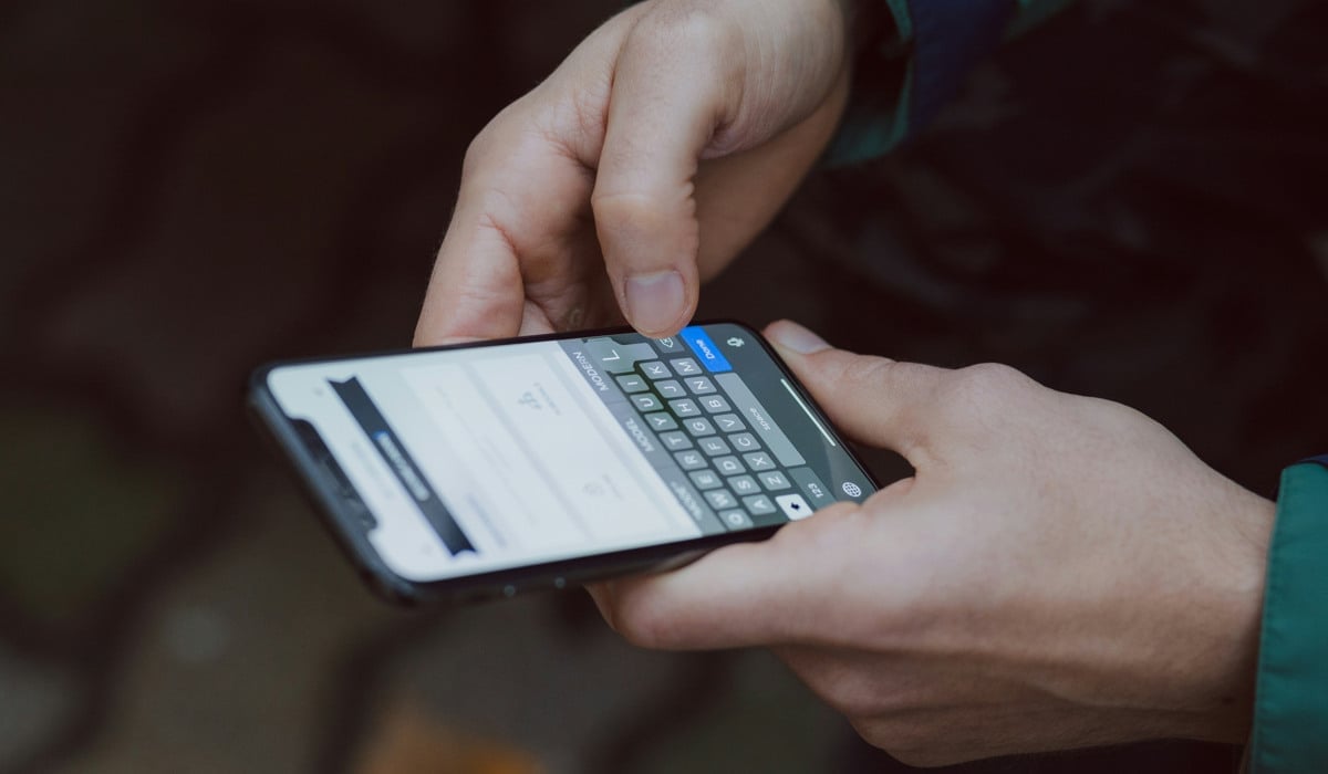 En person som håller en mobiltelefon i handen