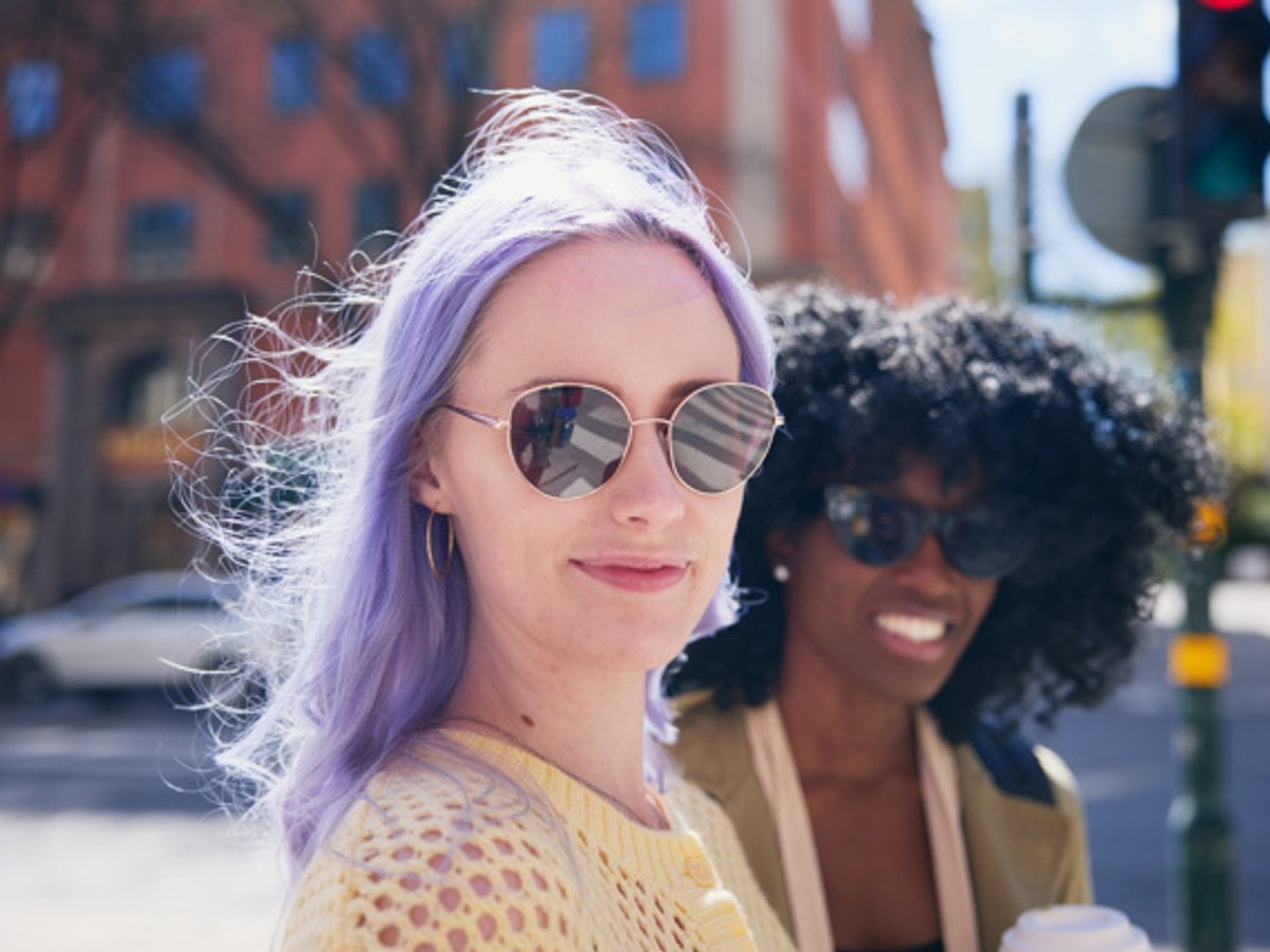 Två unga kvinnor i solglasögon som tittar in i kameran.