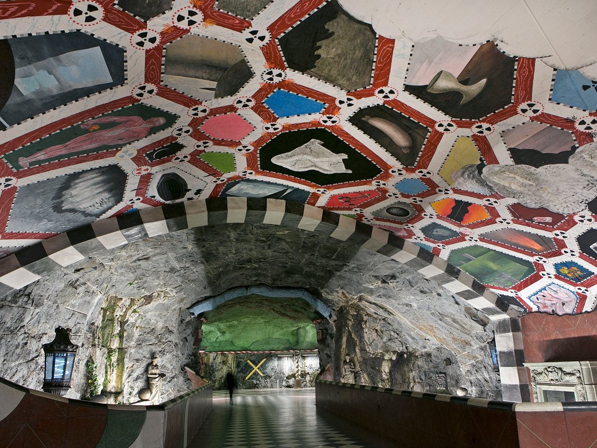 Färgglad konst i taket i en underjordisk tunnelbanestation. Mönstrat stengolv.