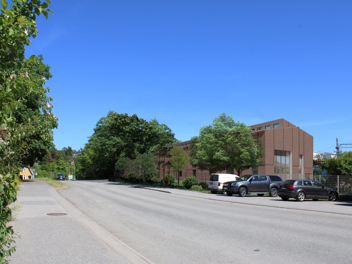 En lägre brun byggnad omgivet av flera träd.