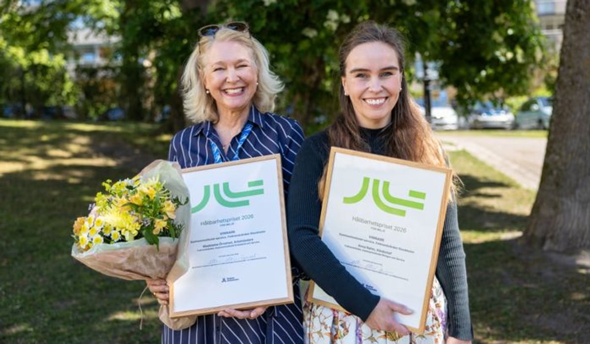 Två kvinnor håller blommor och plaketter i sina händer.