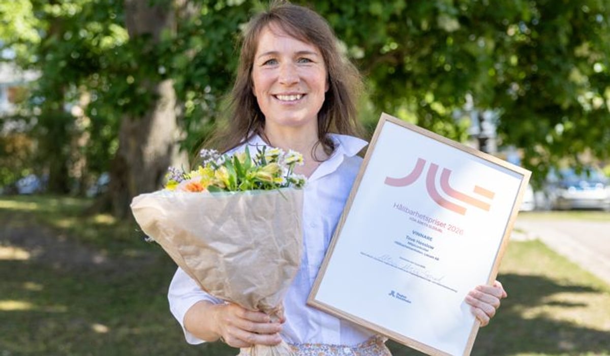 En kvinna håller i en blombukett och ett certifikat.
