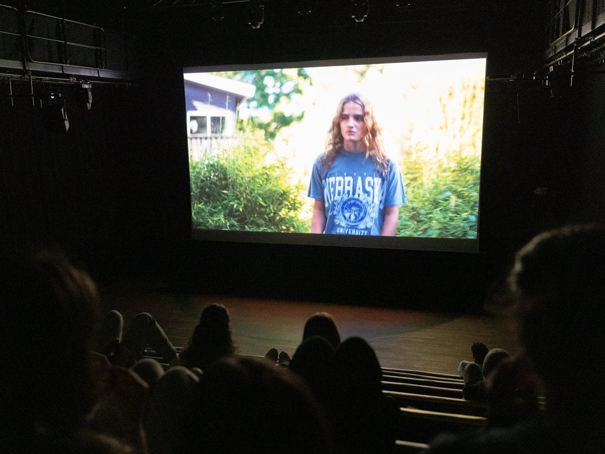 En biosalong med barn och unga som tittar på en film. På bioduken syns en tjej med långt hår och t-shirt.