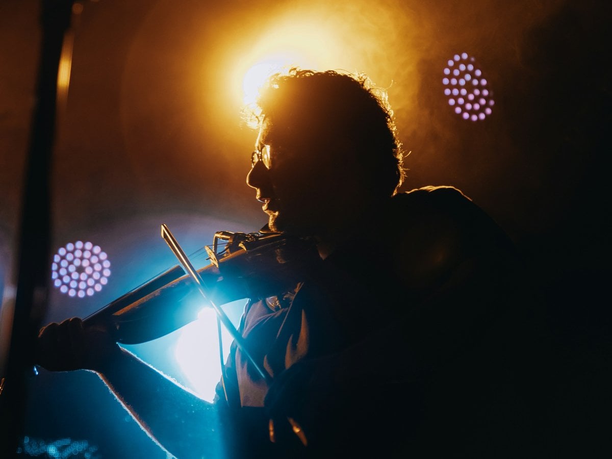 En person i motljus spelar instrument på en scen
