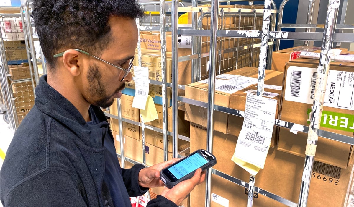 Man står i lager och tittar på mobilskräm.